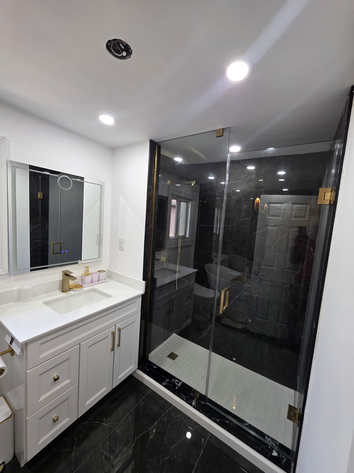 Completed Scarborough bathroom remodel with a glass shower, dark tile, and white vanity